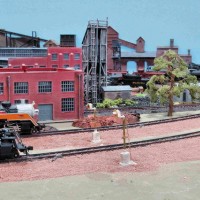 Two steam locomotives passed the Photo cells behind the Roundhouse and the Search Light signals have turned red on the double mainline track. The Switching Yard is in the background.
