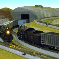 A coal train waits for a freight to clear a tunnel.