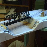 BRIDGE AND PIERS FITTED ACROSS THE HARBOUR AND A PAPER MOCK-UP OF THE STATION BUILDING.