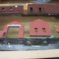 THE PAINTED AND WEATHERED PIECES OF MY LASER-CUT WOOD LOCOMOTIVE MAINTENANCE BUILDING. THE PATCH ABOVE THE DOOR IS BASED ON THE PROTOTYPE.